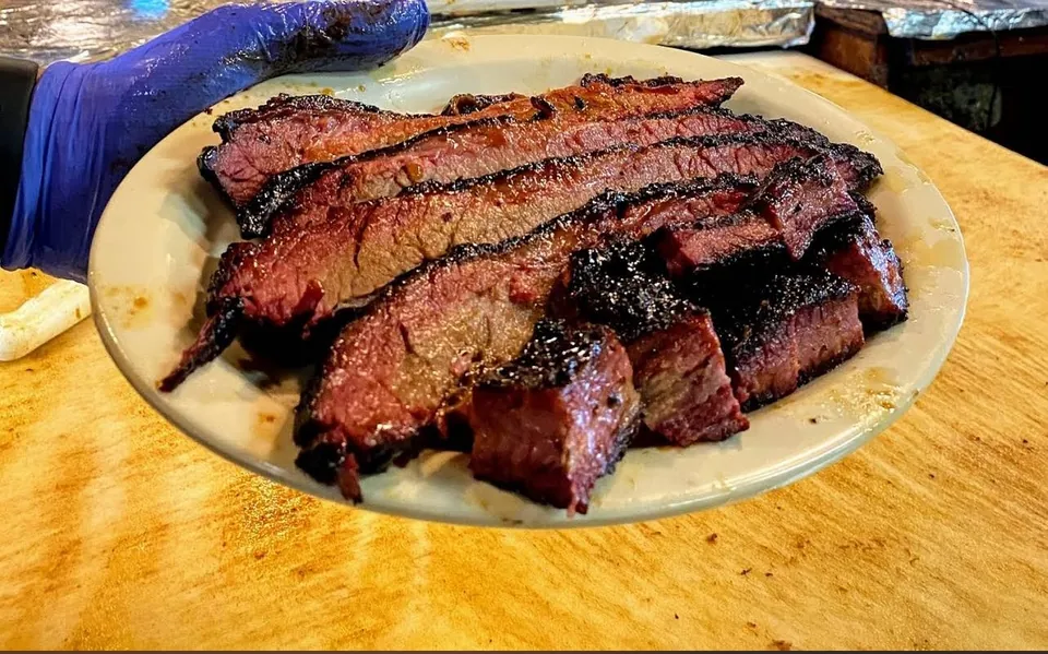 Sliced Texas brisket with a dark bark on a wooden board.