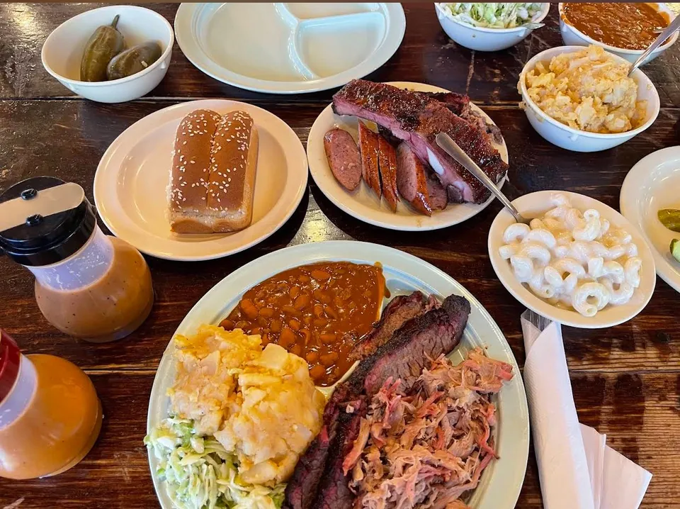 A family-style spread of Texas barbecue with sides on a wooden table.