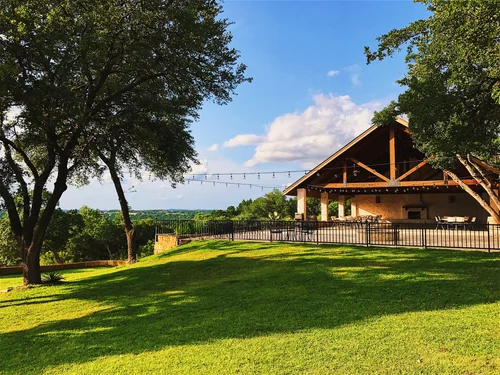 The hilltop pavilion and lawn at Driftwood Estate Winery, strung with lights under the live oaks.