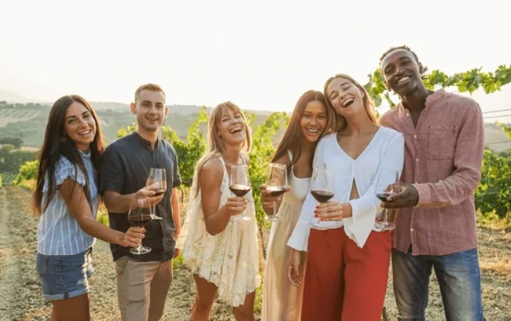 A group of friends with wine glasses among the vines on a private tour.
