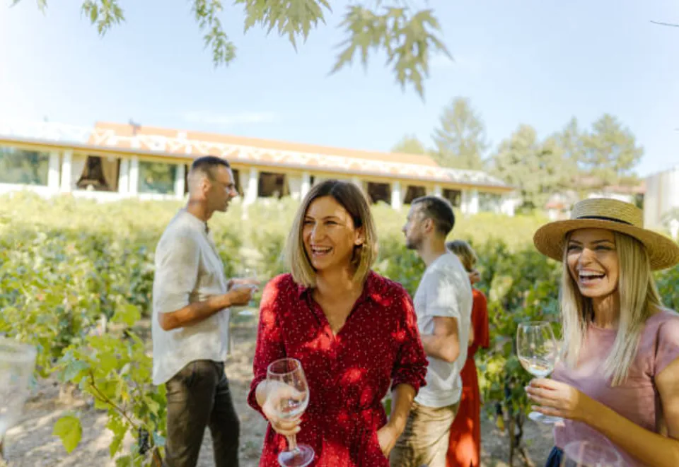 Guests standing together with wine glasses among the vines.