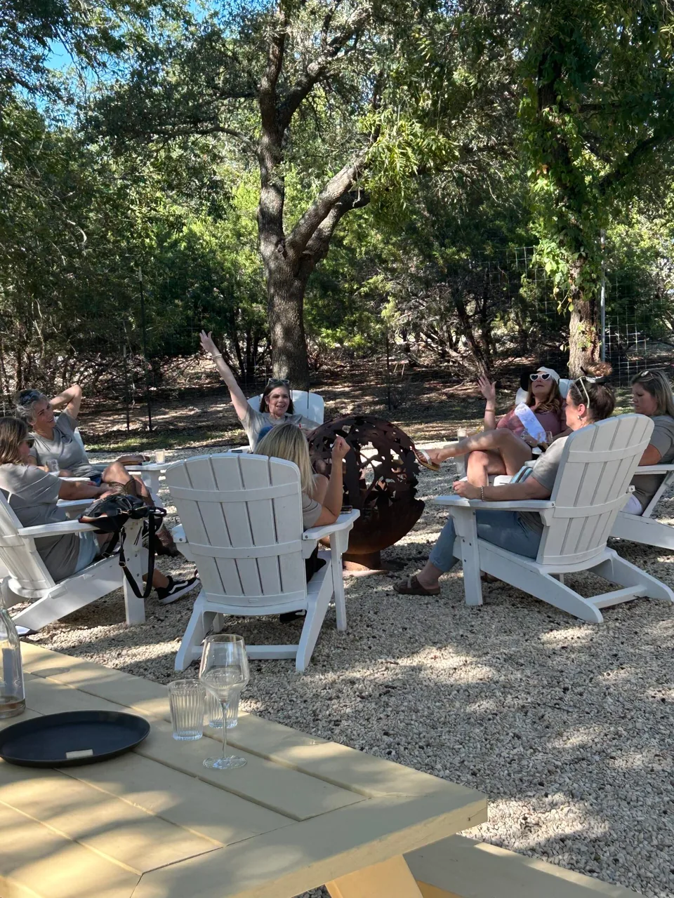 Adirondack chairs under live oaks on a winery lawn.